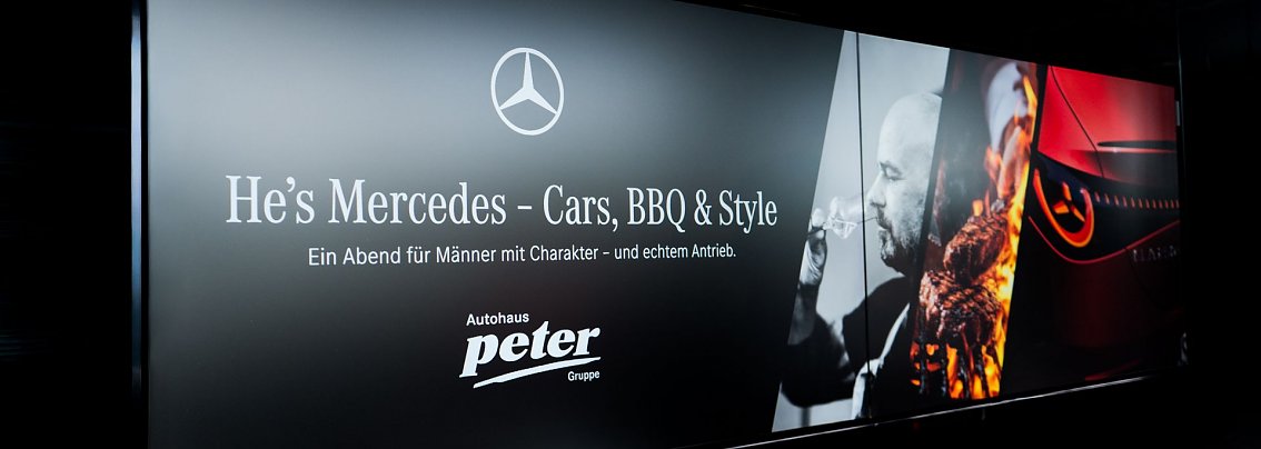 Ein schwarzes Banner mit dem Mercedes-Logo und der Aufschrift „Hes Mercedes  Cars, BBQ & Style. Ein Abend für Männer mit Charakter  und echtem Antrieb.“ Rechts sind ein Mann mit Weinglas, ein Grillfeuer und der Scheinwerfer eines Mercedes-Autos abgebildet.