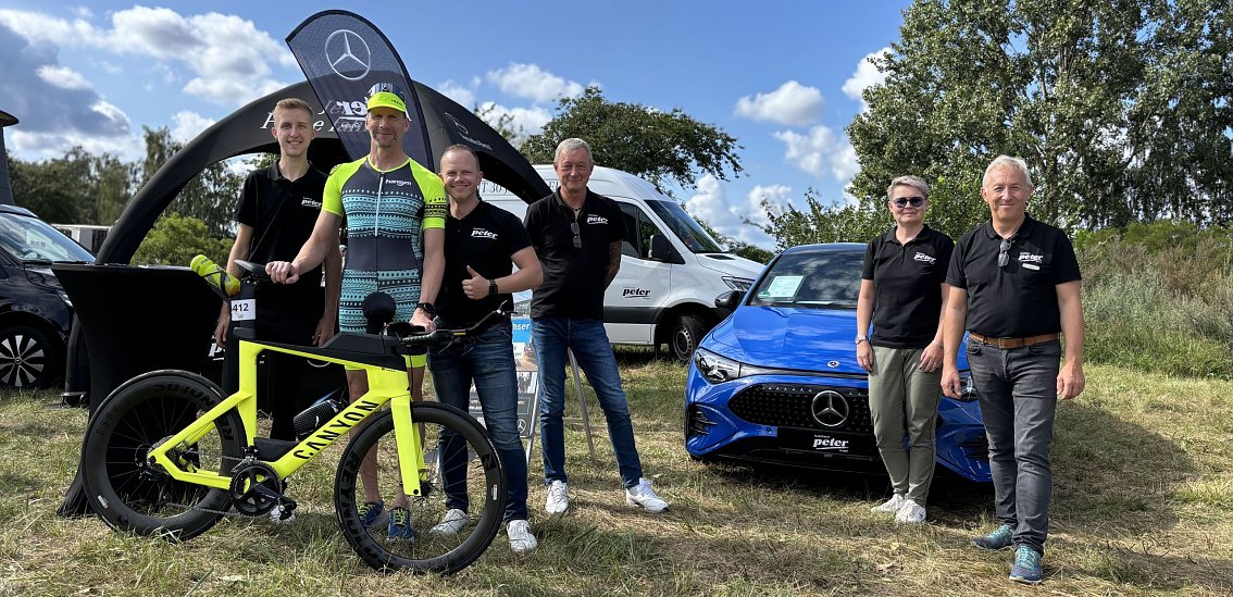 Gruppenfoto vom #TeamPeter und einem traditionellen Teilnehmer vor dem Autohaus Peter Stand.