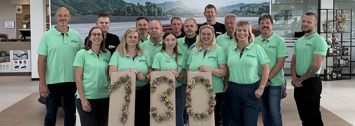 Teamfoto der Skoda Crew in überwiegend türkisfarbenen T-Shirts; devor eine 130 aus gebundenen Blumen.