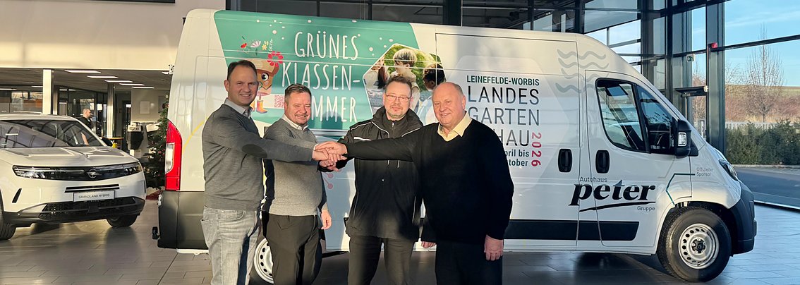 Vier Männer stehen in einem Autohaus vor einem weißen Citroen Jumper und lächeln in die Kamera.