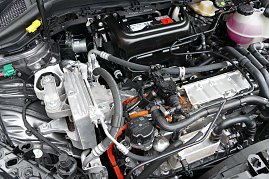 Blick in den Motorraum eines E-Fahrzeuges. Gut zu erkennen sind die Hochvolt-Trennstelle (gr&uuml;n) und die HV-Kabel (orange). 