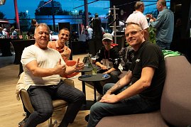 Vier Personen, darunter ein Kind mit Mercedes-Cap, sitzen entspannt in einer Lounge-Ecke. Ein Mann im weißen Shirt zeigt beide Daumen hoch.