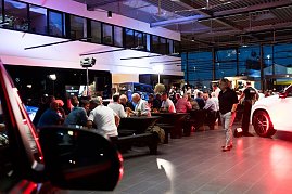 Abendstimmung im Showroom: Viele Gäste sitzen an langen Tafeln, während im Hintergrund Fahrzeuge und Mercedes-Displays beleuchtet sind.