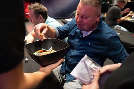 Ein Mann zieht ein buntes Los aus einer Schüssel, die ihm ein Helfer hinhält.