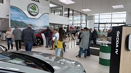 Besucherinnen und Besucher im Autohaus Autowelt Peter während der Jubiläumsfeier zu 130 Jahren Škoda. Im Ausstellungsraum stehen Fahrzeuge, Kranzdekorationen und ein Tisch mit Sektgläsern.
