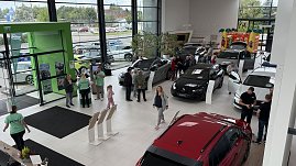 Blick von oben in den Ausstellungsraum des Autohauses Autowelt Peter während der Jubiläumsfeier zu 130 Jahren Škoda. Besucherinnen und Besucher schauen sich verschiedene Fahrzeuge an, Mitarbeitende in grünen Shirts beraten. Im Hintergrund steht eine bunte Hüpfburg für Kinder.