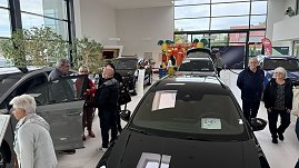 Besucherinnen und Besucher betrachten ausgestellte Škoda-Fahrzeuge im Autohaus Autowelt Peter. Im Hintergrund ist eine bunte Hüpfburg für Kinder zu sehen.
