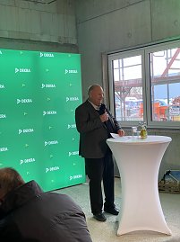 Helmut Peter steht vor einem grünem Dekra-Banner und spricht ins Mikrofon