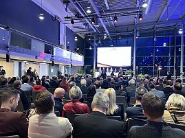 Gro&szlig;es Publikum in einer Messehalle, vorne B&uuml;hne mit Panel und Leinwand bei der Automobil Messe Erfurt.