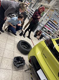 3 Frauen stehen neben einem gelben Peugeot 208, auf dem Fu&szlig;boden liegt ein Rad