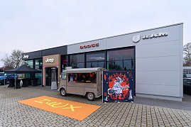 Autohaus mit Jeep-, Dodge- und RAM-Showroom, davor Foodtruck und Eventposter Hex.