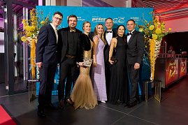 Gruppe elegant gekleideter G&auml;ste vor Sponsorenwand bei Event.