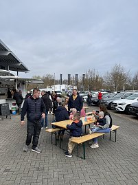 Besucher des Ostermarktes lassen es sich draußen auf Bierzeltgarnituren schmecken.