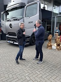 Frank Hentschel und René Pfeuffer stehen vor dem Actros, beide am Mikrofon und erklären technische Details der Sattelzugmaschine.