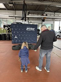 Ein Mädchen wirft in einer Werkstatt Sandsäckchen in Autoreifen.