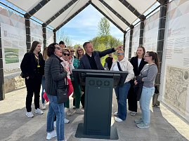 Ein Mann erkl&auml;rt mehreren Frauen etwas und zeigt auf eine Infotafel.