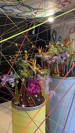 Kunstvoll inszenierte Blumenarrangements und viele bunte, durch den Raum gespannte Bindf&auml;den.