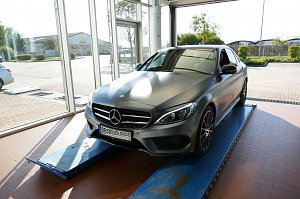 Werkstattbereich im Mercedes-Benz Autohaus Bernburg, ein grauer Mercedes-Benz steht auf einer Hebeb&uuml;hne vor gro&szlig;en Glasfenstern, im Hintergrund Au&szlig;enbereich sichtbar.