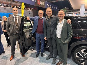 Vier Männer (u.a. Mario Voigt und Andreas Peter) stehen lächelnd neben einem schwarzen Auto mit geöffneter Tür. Im Hintergrund sind die Logos von Opel, Volvo und Renault Trucks auf Bannern zu erkennen.