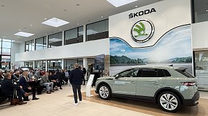 Der neu vorgestellte Škoda Elroq steht in voller Größe im Ausstellungsraum. Im Hintergrund sitzen Gäste und hören dem Vortragenden zu. Über dem Auto hängt das große Škoda-Logo.