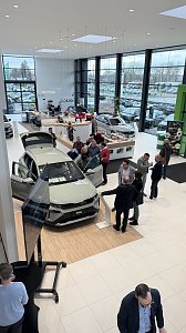 Blick von oben auf den neuen Škoda Elroq im Showroom. Gäste stehen um das Fahrzeug, schauen hinein oder diskutieren. Links im Bild ein Präsentationsbildschirm.