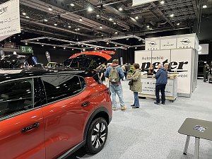 Besucher stehen vor dem Info-Counter von Autohaus Peter. Daneben ein rotes Opel-Fahrzeug mit geöffnetem Kofferraum.