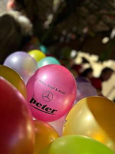 Mehrere bunte Luftballons mit der Aufschrift ‚Helau, Alaaf & Ahoi!‘ und dem Autohaus-Peter-Logo, im Vordergrund ein pinkfarbener Ballon im Fokus.