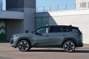 Linke Seitenansicht des grauen Citro&euml;n C5 Aircross, geparkt vor einem modernen Geb&auml;ude.