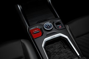 Nahaufnahme der Mittelkonsole mit W&auml;hlrad f&uuml;r Fahrstufen (R, N, D, P), rotem Select Terrain-Schalter, elektronischer Parkbremse und Ablagefl&auml;che mit Jeep-Logo.