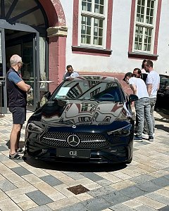 Schwarzer Mercedes CLE steht vor einem historischen Gebäude in Heiligenstadt. Mehrere Männer begutachten den Wagen, das Auto spiegelt die Fensterfront des Gebäudes.