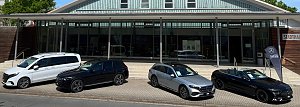 Vor der Stadthalle Wittenberg sind vier Mercedes-Benz-Fahrzeuge in einer Reihe ausgestellt: ein weißer Van, ein schwarzer SUV, ein silberner Kombi und ein schwarzes Cabriolet mit offenem Verdeck. Rechts steht eine schwarze Fahne mit dem Logo „Autohaus Peter“.