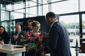 Lilly Hecker, frisch ausgebildete Automobilkauffrau und Jahrgangsbeste, erhält einen Blumenstrauß von Geschäftsführer Andreas Peter. Im Hintergrund applaudieren weitere Mitglieder der Geschäftsführung.