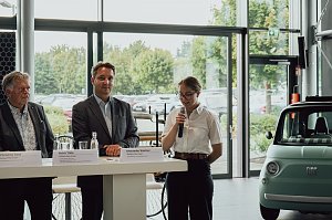 Lilly Hecker steht am Rednerpult mit einem Mikrofon und spricht zu den neuen Auszubildenden. Neben ihr stehen Mitglieder der Geschäftsführung der Autohaus-Peter-Gruppe.