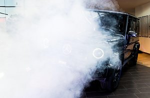 Eine schwarze Mercedes G-Klasse wird in Szene gesetzt. Dichter weißer Nebel und Scheinwerferlicht verdecken teilweise das Auto.