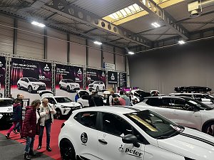 Mehrere weiße Mitsubishi-Fahrzeuge in einer Messehalle, dazwischen interessierte Messebesucher, vorn ein schwarzes Autocenter Peter Logo.