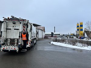 Verkaufsberater vom Autohaus Peter André Schmidt steht auf der Trittstufe eines Müllfahrzeugs während der Fahrt durch ein Industriegebiet.