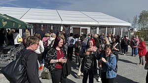 Mehrere Frauen stehen vor einem großen Zelt und unterhalten sich.