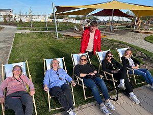 5 Frauen in Liegestühlen, dahinter steht ein in rot gekleideter Gästeführer der Landesgartenschau.