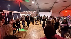 Viele Personen auf einer Tanzfläche am Abend.