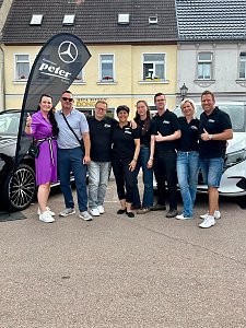 Man sieht das Team vom Autohaus Peter zwischen zwei Fahrzeugen stehen.