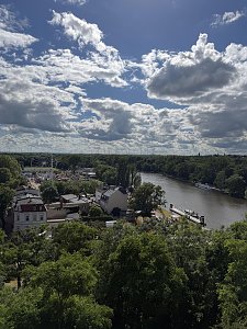 Blick auf die Saale und den Schausteller-Park. Der Himmel ist blau und mit Wolken durchzogen, im unteren Bild sieht man viele gr&uuml;ne B&auml;ume.
