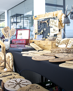 Marktstand mit handgefertigten Holzarbeiten, Schmuck, gravierten Brettern und dekorativen Holzscheiben.