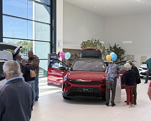 Besucher informieren sich im �koda-Showroom &uuml;ber den roten �koda Elroq mit ge&ouml;ffneten T&uuml;ren und ge&ouml;ffneter Heckklappe.
