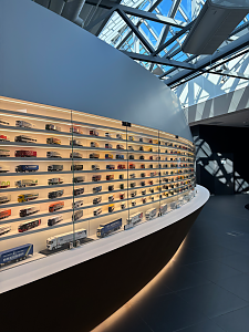 Eine riesige, geschwungene Vitrinenwand präsentiert unzählige Lkw-Modelle im Miniaturformat auf beleuchteten Regalböden.
