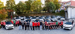 Spielerinnen des Thüringer HC und Vertreter der Peter Gruppe posieren gemeinsam vor einer Flotte weißer Opel-Fahrzeuge im THC-Design.