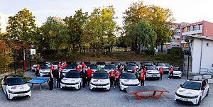 Spielerinnen des Thüringer HC in roten Trikots und Vertreter der Peter Gruppe stehen zwischen gebrandeten Opel-Fahrzeugen auf einem Sportgelände.