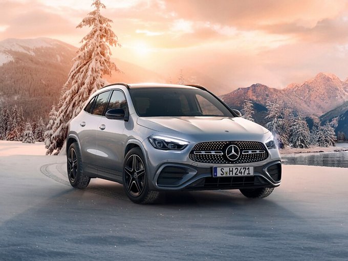 Mercedes-Benz GLA steht vor winterlicher Berglandschaft mit schneebedeckten Bäumen bei warmer Abendstimmung.